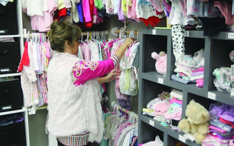 Connie Landreneau, director of New Life Pregnancy Center in Mamou, sorts through items for sale in the baby boutique. The items can be purchased by mothers who participate in services offered by the center. (Gazette photo by Tony Marks)