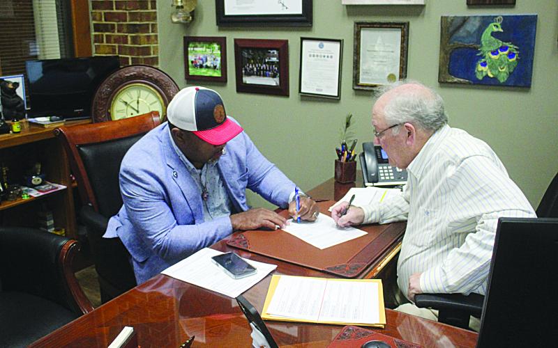 Ville Platte Mayor Ryan LeDay Williams (left) was the first candidate to qualify for the November 3, election. He is pictured as he signs the paperwork with Evangeline Parish Clerk of Court Randy Deshotel (right). Qualifying continues until Friday, August 7, at 4:30 p.m. (Gazette photo by Tony Marks)