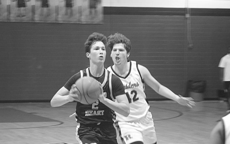 With Carter Guillory (42) nipping at his heels, Sacred Heart’s Ellis Chapman (2) looks to pass the basketball to a Trojan teammate. (Gazette photo by Tony Marks)