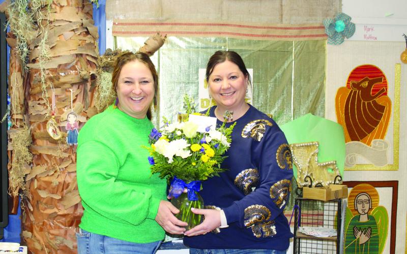 Sacred Heart Elementary Principal Danielle Ardoin (right) presents flowers to the school’s teacher of the year, Jeanne Harmon (left).