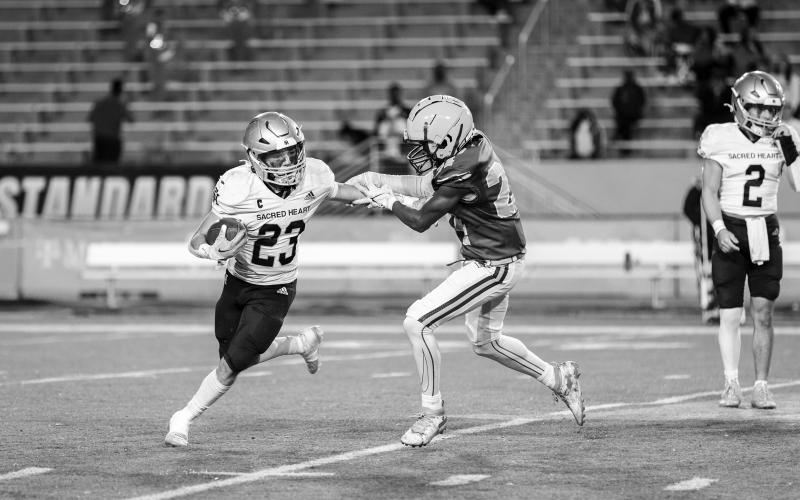 Jude Hebert (23) looks to turn a corner and find additional running room in Sacred Heart’s playoff loss to Southern Lab. (Photo by Angela deVille)
