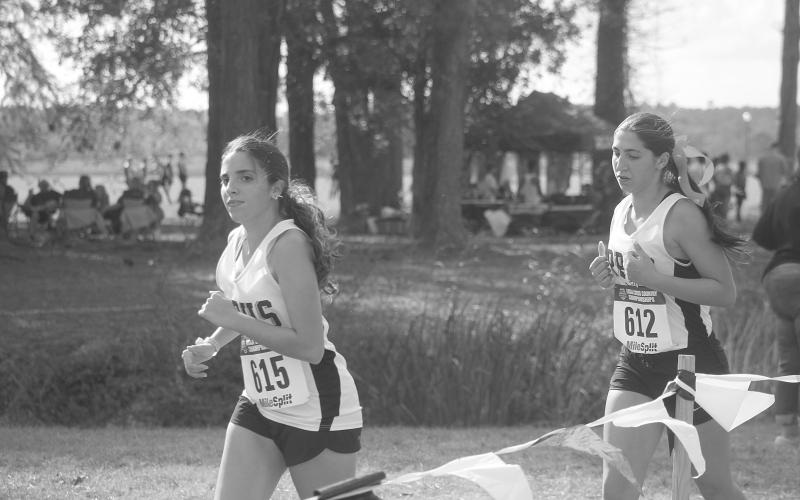 Cheyanne Maricle (615) and Dulcie Fontenot (612), both of Pine Prairie High School, are pictured as they wind their way down the three-mile course at the state cross country meet in Natchitoches. (Gazette photo by Tony Marks)
