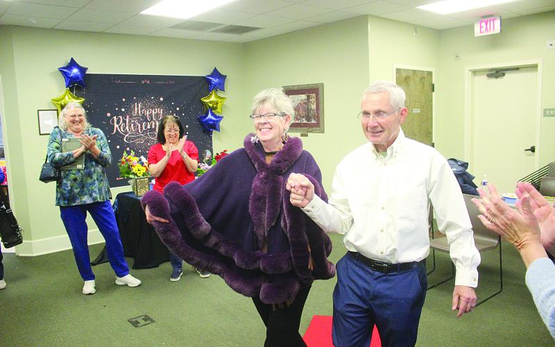 Suzy Lemoine (left) and her husband, Phil, walk down the ceremonial red carpet during a celebration of her 26-year career at the Evangeline Parish Library. (Gazette photo by Tony Marks)