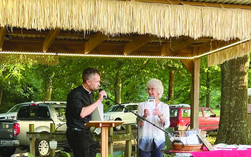 Carrol LaFleur is pictured on the right as she talks about books on the life of Fr. Verbis LaFleur, who was declared a servant of God by the Diocese of Lafayette. Pictured on the left of Fr. Travis Abadie, pastor of St. Francis Regis Catholic Church of Arnaudville. (Photo courtesy of St. Bernard Catholic Church)