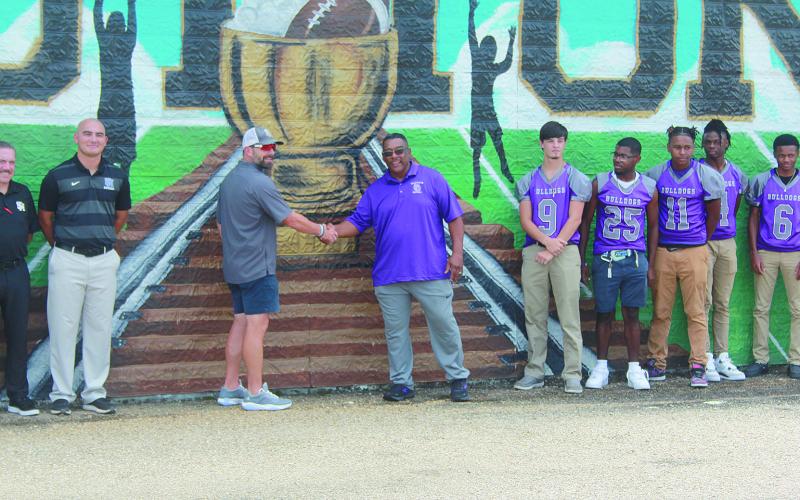 Sacred Heart head coach Josh Harper (left) and Ville Platte High head coach Roy Serie (right) exchange a hand shake in front of the Tee Cotton Bowl mural. (Gazette photo by Tony Marks)