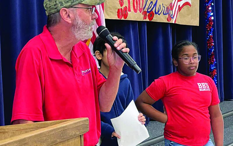 David Bertrand, a veteran of the U.S. Marine Corps, speaks to the student body at W. W. Stewart Elementary during the school’s recent Salute to Veterans event. The students are (from left) Cyan Contreras and Harleigh Richardson.