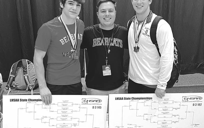 Bearcat wrestling coach Ben Bertrand congratulates seniors Luc Johnson (left) and Christian Bergeron (right) on their individual state championships in their respective weight classes. Both claimed titles for the second consecutive year. (Photo by Tracy Veillon)