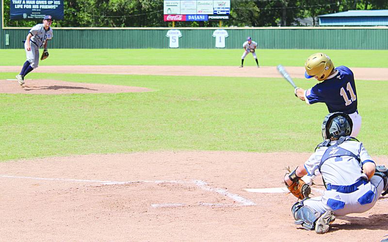 Sacred Heart leadoff hitter and starting shortstop Gabe Wilmouth (11) finishes his swing in the Trojans’ deciding game against Ascension Christian on Saturday, April 30.  (Gazette photo by Rhett Manuel)