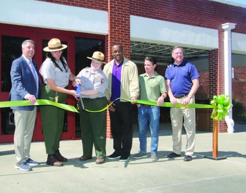 Cutting a ribbon marking the reopening of the Prairie Acadian Cultural Center on Friday were, from left, Scott Fontenot  Eunice mayor; Laura McDonald and Lainey Binnix, park rangers; Herman Fuselier, parish tourism director; Justin Lemoine, executive director of the Atchafalaya National Heritage Area; and Dwight Jodon, Eunice Rotary Club member. (LSN photo by Harlan Kirgan)