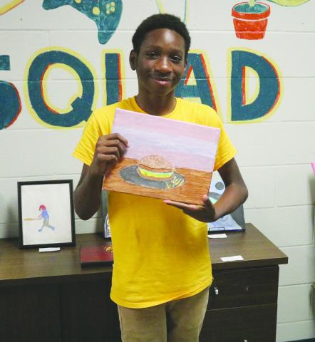 Derrion Denton, a seventh grade student of Evangeline Reimagine Academy, shows off one of his pieces of art which was on display on Wednesday, May 22. (Gazette photo by Tony Marks)