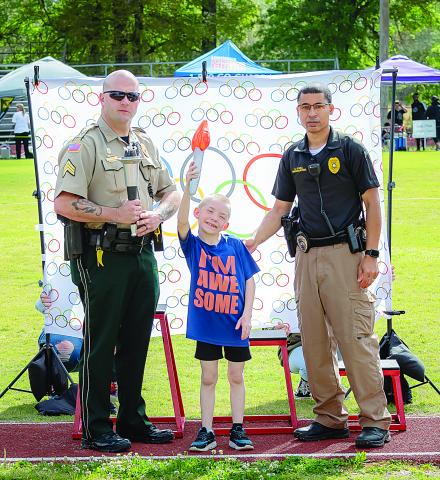 James Stephens Montessori student James LeBlanc (center) hoists the Special Olympic flame at the event held Tuesday, March 29, in Basile. Also pictured are Basile police officer Daniel Crum (left) and Ville Platte police officer Pat Hall. (Photo courtesy of Tim Comeaux)