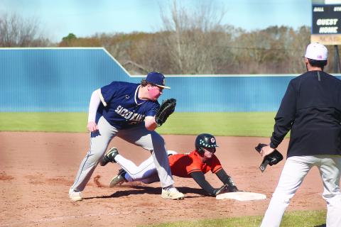 Weston Byrd (10) slides underneath the tag from Sacred Heart first baseman Liam Vidrine (28) as the Pine Prairie Panthers took on the Trojans in the Perry Pitre Baseball Jamboree. (Gazette photo by Tony Marks)