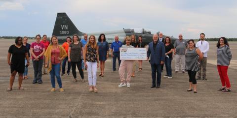 Retired Col. Kevin Melton and 2021 Airshow director Mary Jo Bayles, seen here holding an oversized check, are surrounded by the grant recipients, who include Christina Lejeune, Basile High. Airshow board members, seen in the back row, joined in for the presentation. (Photo submitted) 