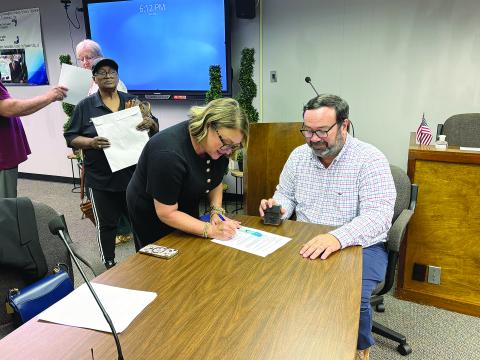 Cheri Fontenot (center) is pictured as she signs her contract to officially become the new school superintendent. Seated is Assistant District Attorney Jacob Fusilier, who notarized the contract. Also pictured on the left is Evangeline Parish School Board Vice President Sheila Joseph. (Gazette photo by Tony Marks)