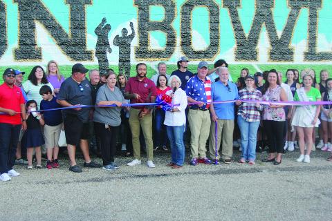 Among those pictured at the Tee Cotton Bowl mural dedication ceremony are (from left) Chris and Connie Lamke, Thaddaeus Arvie, Dr. Gwen Fontenot, Tim Fontenot, Ronnie and Joan Landreneau, Renee Brown, and Queen Cotton Shelbi Rials. (Gazette photo by Tony Marks)