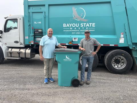 NEW TRASH SERVICE COMING TO EVANGELINE PARISH - Bayou State Waste will begin taking over garbage collection for Evangeline Parish starting June 30. Evangeline Parish Solid Waste Director Pat Derouselle (left) and Bayou State owner Jake Lavergne (right) are shown with one of the cans that each household in the parish will receive as part of the new contract with the company. (Gazette photo by Heather Bogard)