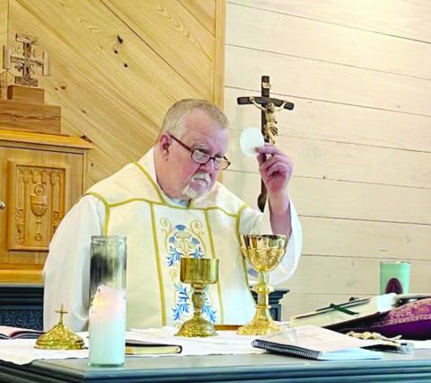 Fr. Greg Downs, of St. Peter Catholic Church in Pine Prairie and St. Theresa Catholic Church in St. Landry, is pictured as he elevates the Blessed Sacrament during a recent Mass. (Photo courtesy of St. Peter St. Theresa)