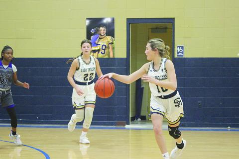 Emily Stagg (10) takes the basketball toward the net after receiving an inbound pass from Lady Trojan teammate Kali Shiver (22). (Gazette photo by Rhett Manuel)