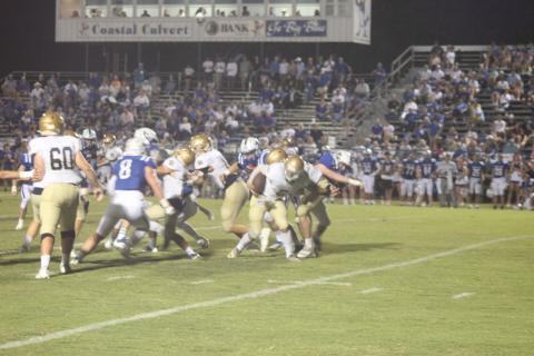 Sacred Heart’s signal caller Ethan Karonika (5) tries to stay on his feet as he is met by the St. Ed’s defense last week in Eunice. Karonika and the rest of the Trojans are hosting Opelousas Catholic on homecoming night tomorrow for the district title. (Gazette photo by Rhett Manuel)