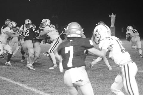 The Sacred Heart defense led by Hayden Droddy (7) and Beau St. Romain (52) combines for a stop deep inside Blue Jay territory in the Trojans’ playoff win against St. Ed’s last week. (Gazette photo by Rhett Manuel)