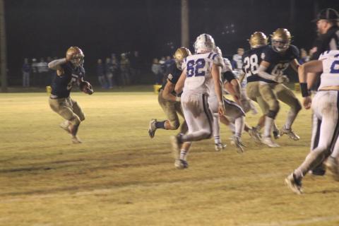 Sacred Heart quarterback Ethan Karonika (5) finds a running lane thanks to a block from his offensive line in the Trojans’ playoff win against disrtrict rival St. Edmund. (Gazette photo by Rhett Manuel)