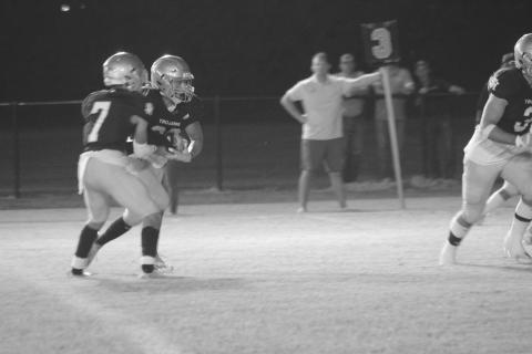Trojan quarterback Hayden Droddy (7) hands the football off to Ike Perry (22) in Sacred Heart’s district opening loss last week. (Gazette photo by Rhett Manuel)