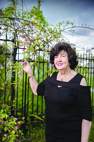 Peggy Martin stands beneath the Peggy Martin rose growing along a fence at her home in Gonzales, Louisiana. The rose was named for Martin after it survived being inundated with water for several weeks on her Plaquemines Parish property after Hurricane Katrina in 2005. (Photo by Eddy Perez/LSU)