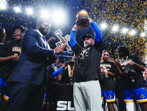 McNeese head men’s basketball coach Bill Armstrong (center) hoists the SLC Championship Trophy after the Cowboys defeated Stephen F. Austin. (Photo courtesy of Matthew Bonnette)