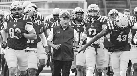 McNeese football coach Matt Viator runs onto the field with his team before a game last season. (Photo courtesy of McNeese Athletics)