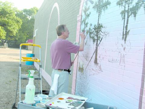 Local artist Waven Boone is shown filling in the sketched panels of his mural “The Spirit of Ville Platte.” (Gazette file photo by Heather Bogard)
