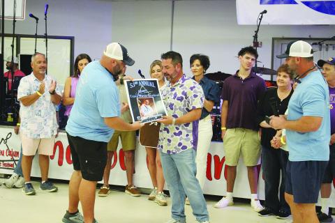 Kevin Naquin (right) accepts his commemorative poster from Mamou Cajun Music Festival Association Vice President Kade Verrette (left). (Gazette photo by Tony Marks)