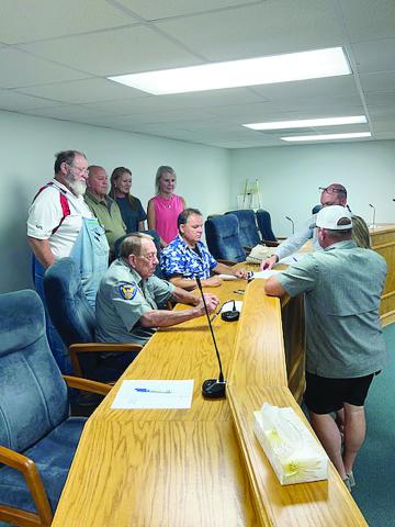 After the Pine Prairie Council meeting on Thursday, August 10, a donation of property was signed. Pictured standing on the left (from right) are Councilwoman Tammy Buxton, Kristy Ardoin, and Councilmen Kevin Rodriguez and Gilbert Bordelon; seated on the left (from right) are Mayor Quint West and Chief of Police LC Deshotel; standing on the right are Village Attorney Greg Vidrine and Lelia and Derrick Thrasher. (Gazette photo by Tony Marks)