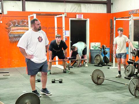 Pine Prairie head football coach Lance Myers (left) watches as members of the team lift weights during summer workouts. (Gazette photo by Tony Marks)