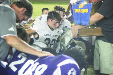 Sacred Heart’s Isaac “Ike” Perry (23) takes a knee during the prayer following Tee Cotton Bowl XVIII earlier this season. (Gazette photo by Rhett Manuel)