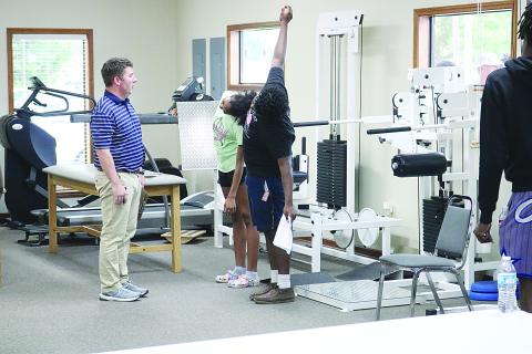 Physical therapist Clay Landreneau (left) checks range of motion on two athletes from Ville Platte High, including Kyle Gallow (right). 