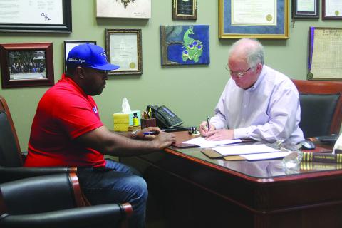 Evangeline Parish Clerk of Court Randy Deshotel (right) notarizes paperwork for Ryan Leday Williams (left), who was the first candidate to qualify for the November election. (Gazette photo by Tony Marks)