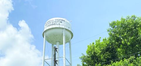 Pictured in the main photo is the Reddell-Vidrine Water System water tower. Pictured in the inset photo is Elizabeth Yvette Jagneaux, a former teacher in Evangeline Parish who worked with Communities Unlimited to restore and rebuild the water system. (Photos courtesy of Communities Unlimited and Elizabeth Jagneaux)
