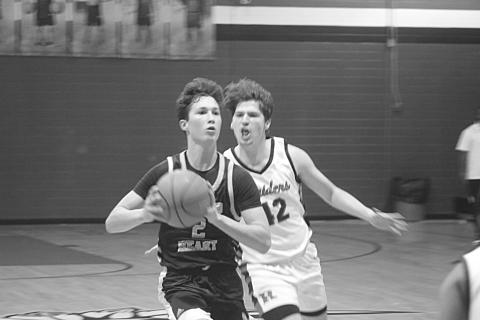 With Carter Guillory (42) nipping at his heels, Sacred Heart’s Ellis Chapman (2) looks to pass the basketball to a Trojan teammate. (Gazette photo by Tony Marks)
