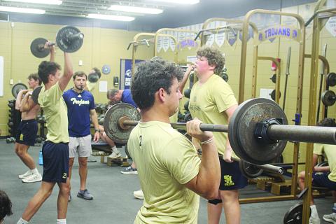 Sacred Heart head football coach Jacob Aguillard (center left) looks on as members of his team lift weights during summer workouts on Tuesday, June 9. (Gazette photo by Tony Marks)