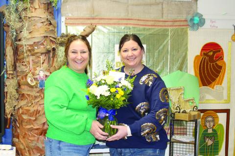 Sacred Heart Elementary Principal Danielle Ardoin (right) presents flowers to the school’s teacher of the year, Jeanne Harmon (left).