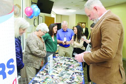 Staff members of Savoy Medical Center look through photographs depicting the hospital’s 75-year history during a celebration held Tuesday, December 16. Among those pictured are Chief Nursing Officer Laurie Manuel, Director of Hospital Operations Danny LaHaye, and Chief Executive Officer Brian Denton. (Gazette photo by Kathy Longino)