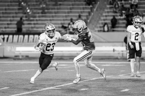 Jude Hebert (23) looks to turn a corner and find additional running room in Sacred Heart’s playoff loss to Southern Lab. (Photo by Angela deVille)