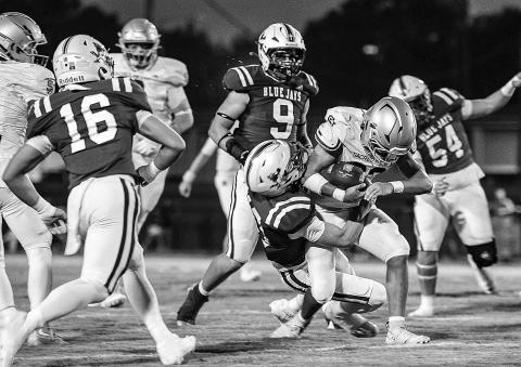 Sacred Heart runner Gavin Patin (22) drags a St. Edmund defender with him as he fights for additional yardage against the Blue Jays. (Photo by Dwight Jodon)
