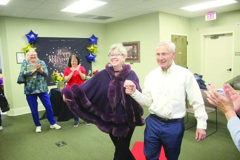 Suzy Lemoine (left) and her husband, Phil, walk down the ceremonial red carpet during a celebration of her 26-year career at the Evangeline Parish Library. (Gazette photo by Tony Marks)