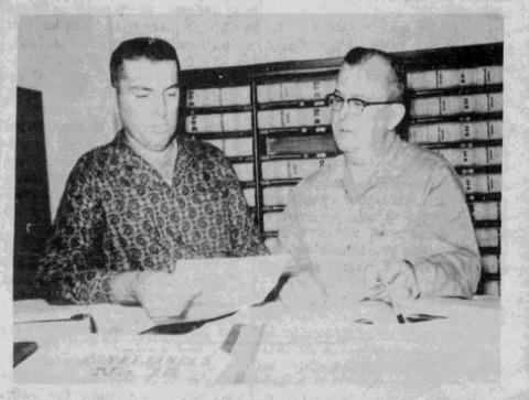 Clerk of Court Walter Lee and Deputy Louis Demoruelle look over legal documents by which president-elect John F. Kennedy transferred mineral holdings in Evangeline Parish to Janet DeRosiers, said to be the hostess-secretary of his personal plane. The mineral rights, acquired in 1951, are on property near Basile and will soon be expiring, unless production is begun within the coming year. (J. Quinn photo and caption - Dec. 29, 1960, Ville Platte Gazette)