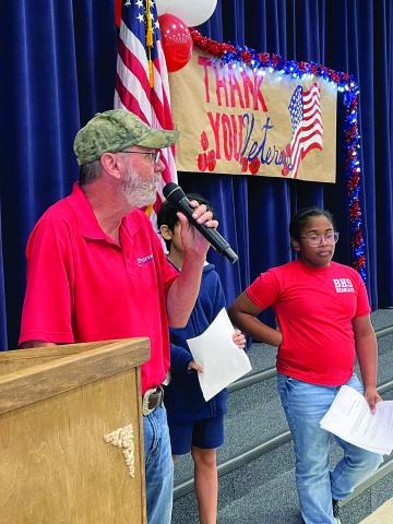 David Bertrand, a veteran of the U.S. Marine Corps, speaks to the student body at W. W. Stewart Elementary during the school’s recent Salute to Veterans event. The students are (from left) Cyan Contreras and Harleigh Richardson.