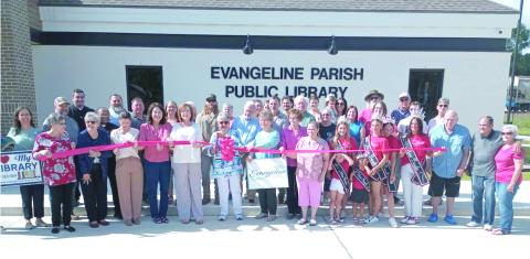 Local and parish library board members and employees, pastors, community leaders, library patrons, and Miss Basile royalty along with contractors who built the new Basile library branch building are gathered around Faye Langley, local representative on the Evangeline Library Board of Control, as she cuts the ceremonial ribbon at the library’s grand opening. 