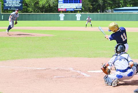 Sacred Heart leadoff hitter and starting shortstop Gabe Wilmouth (11) finishes his swing in the Trojans’ deciding game against Ascension Christian on Saturday, April 30.  (Gazette photo by Rhett Manuel)