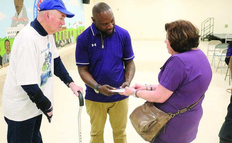 Suzy Fontenot (right) presents new Ville Platte High School head football coach Chris Bland (center) with a copy of Sharpened Iron: The Tee Cotton Bowl Story. Pictured on the left is Tee Cotton Bowl co-founder Tim Fontenot. (Gazette photo by Tony Marks)
