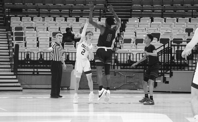 Hayden Deshotel (2) passes the basketball while being defended by Geo Next Generation’s Alonzo Knighten in a Trojan 63-46 win on Saturday.